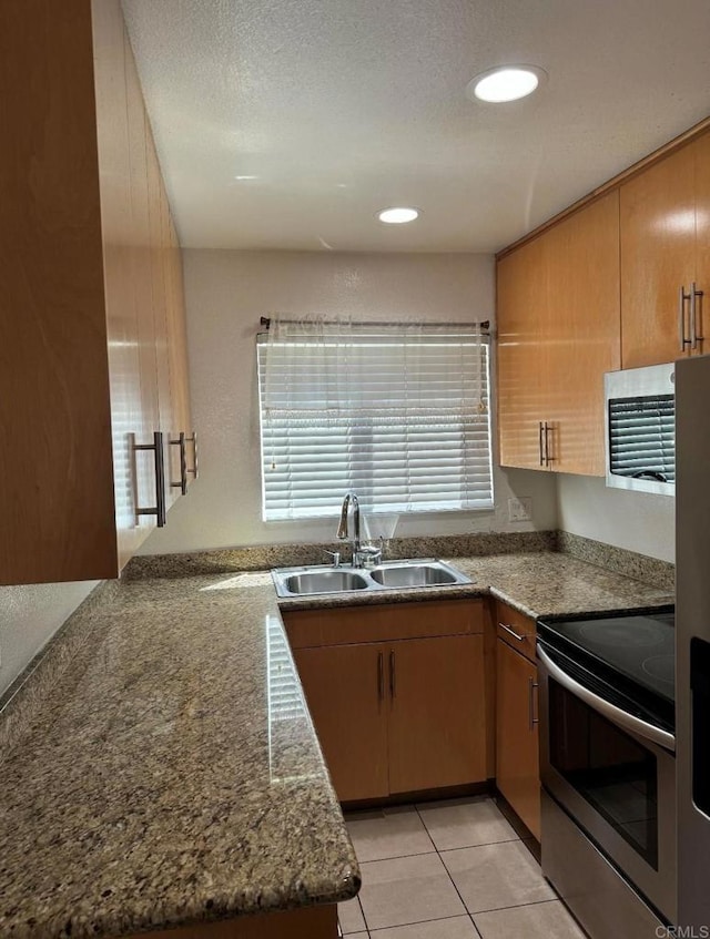 kitchen with sink, appliances with stainless steel finishes, kitchen peninsula, and light tile patterned flooring