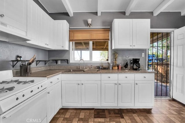 kitchen featuring white range with gas cooktop, beam ceiling, white cabinets, and sink