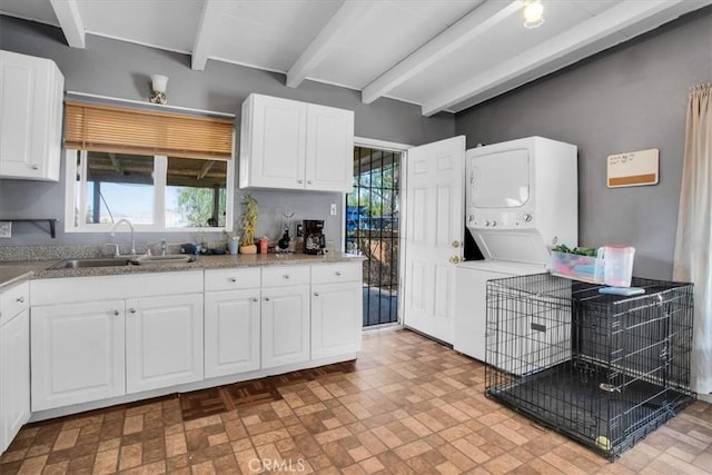 kitchen featuring sink, white cabinetry, and stacked washer / drying machine