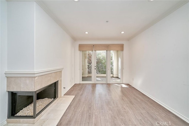 unfurnished living room with light wood-type flooring, a tile fireplace, crown molding, and french doors