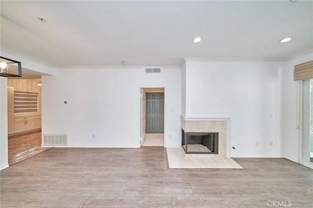 unfurnished living room featuring light wood-type flooring, crown molding, and a fireplace