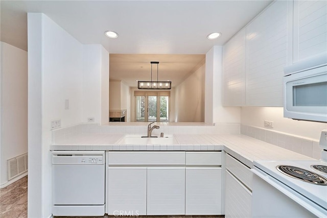 kitchen featuring decorative light fixtures, sink, white cabinets, and white appliances