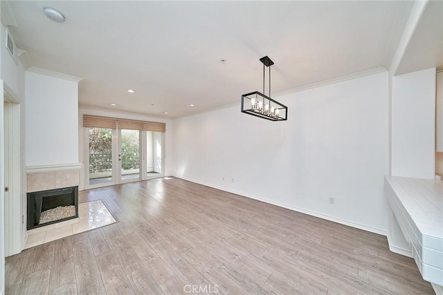 unfurnished living room featuring light wood-type flooring, a tile fireplace, and crown molding