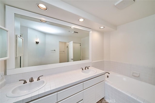 bathroom with a relaxing tiled tub and vanity