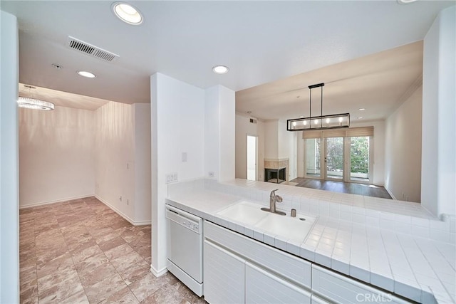 kitchen with sink, an inviting chandelier, white dishwasher, white cabinetry, and hanging light fixtures