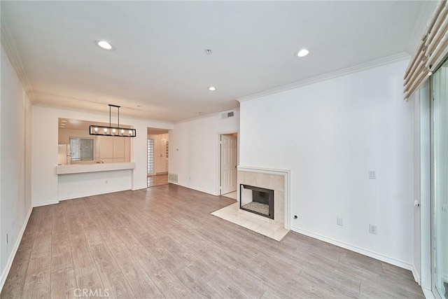 unfurnished living room with a tile fireplace, crown molding, and hardwood / wood-style flooring