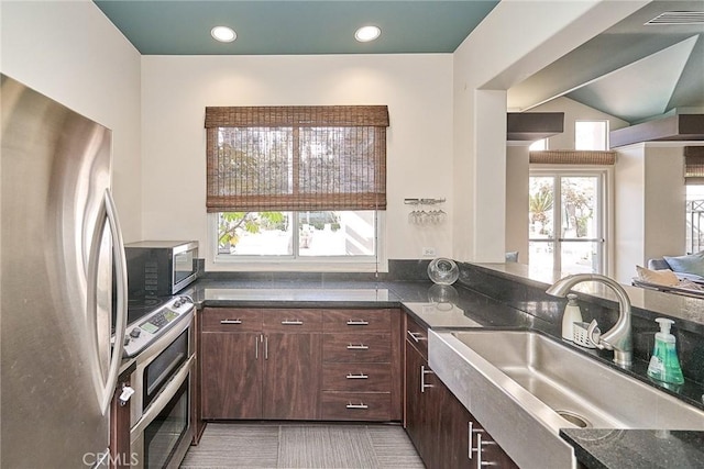 kitchen with light tile patterned floors, sink, dark brown cabinetry, and stainless steel appliances