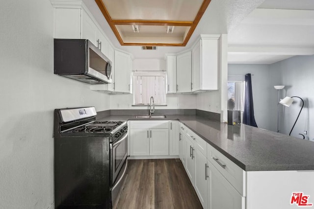 kitchen with black range with gas stovetop, kitchen peninsula, sink, white cabinetry, and dark hardwood / wood-style flooring