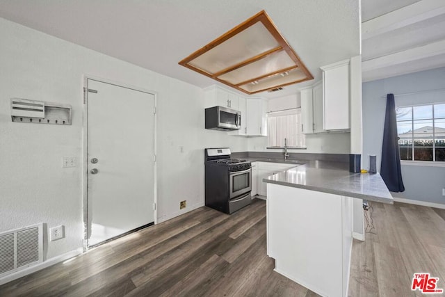 kitchen with kitchen peninsula, a kitchen bar, stainless steel appliances, and white cabinetry