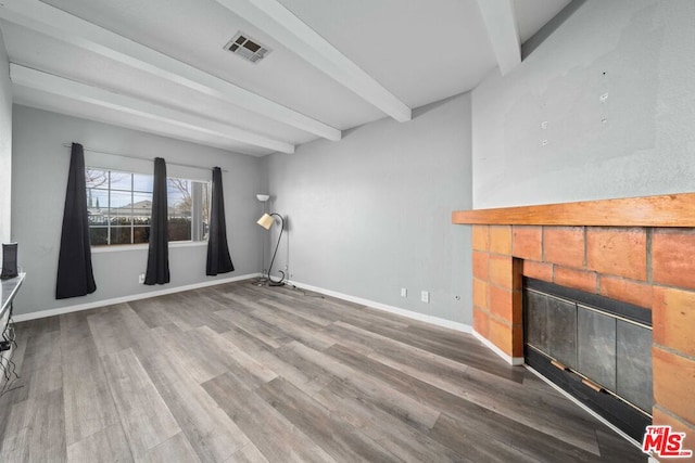 unfurnished living room featuring beam ceiling, a fireplace, and hardwood / wood-style floors