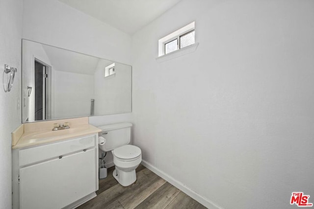 bathroom with toilet, vanity, and wood-type flooring