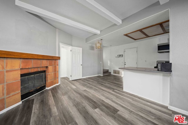 unfurnished living room with hardwood / wood-style flooring and beamed ceiling