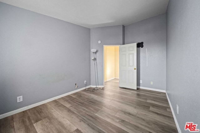 empty room featuring wood-type flooring and a high ceiling