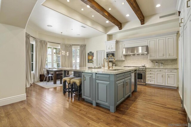 kitchen featuring extractor fan, decorative backsplash, sink, white cabinetry, and a large island