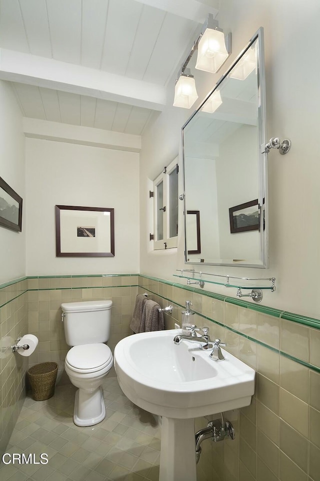 bathroom featuring toilet, wood ceiling, tile patterned flooring, tile walls, and beamed ceiling