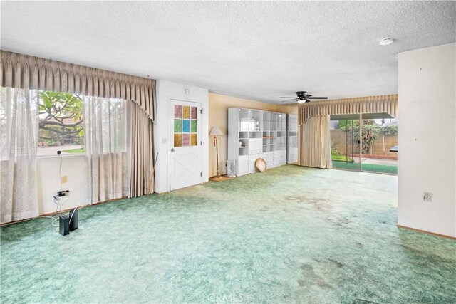 unfurnished living room featuring carpet floors, ceiling fan, and a textured ceiling