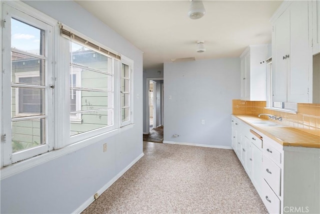 kitchen featuring decorative backsplash, sink, and white cabinetry