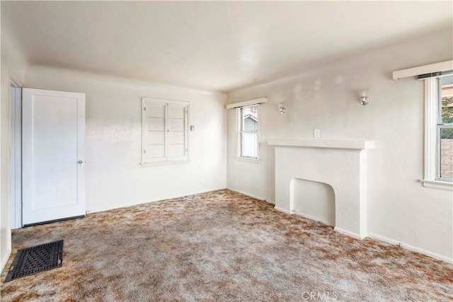 unfurnished living room featuring carpet floors and plenty of natural light