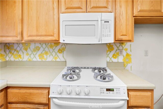 kitchen featuring backsplash and white appliances