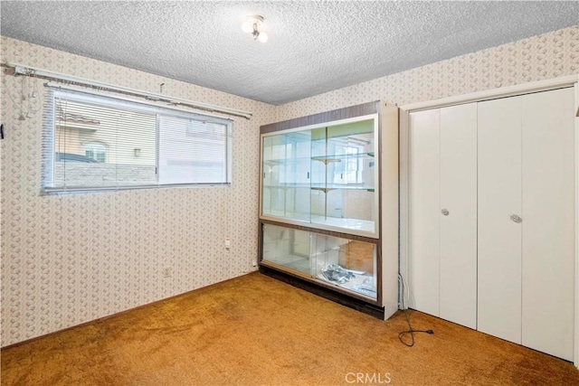 unfurnished bedroom with a textured ceiling, a closet, and light carpet