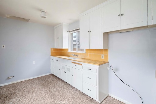 kitchen featuring tasteful backsplash, sink, and white cabinetry