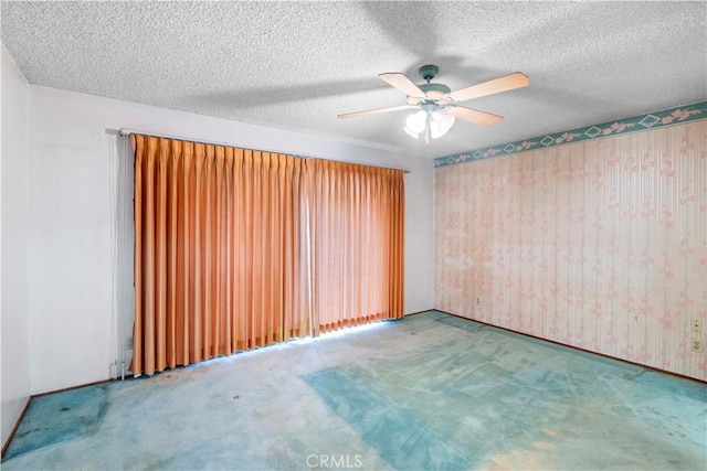 carpeted empty room featuring ceiling fan and a textured ceiling