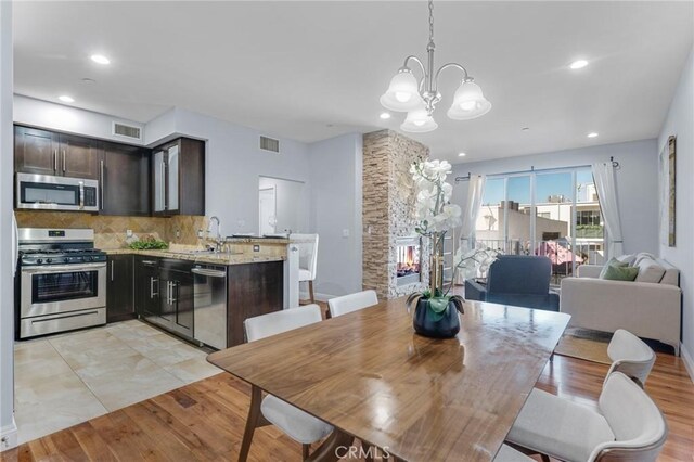 tiled dining area featuring a fireplace, sink, and a chandelier