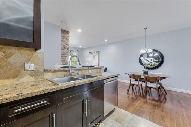 kitchen with stainless steel dishwasher, sink, hanging light fixtures, and dark brown cabinetry