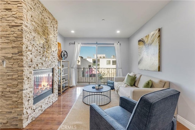 living room with a stone fireplace and hardwood / wood-style floors