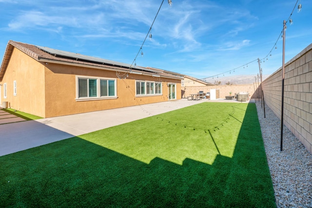 rear view of house featuring a patio area, a lawn, solar panels, and central air condition unit