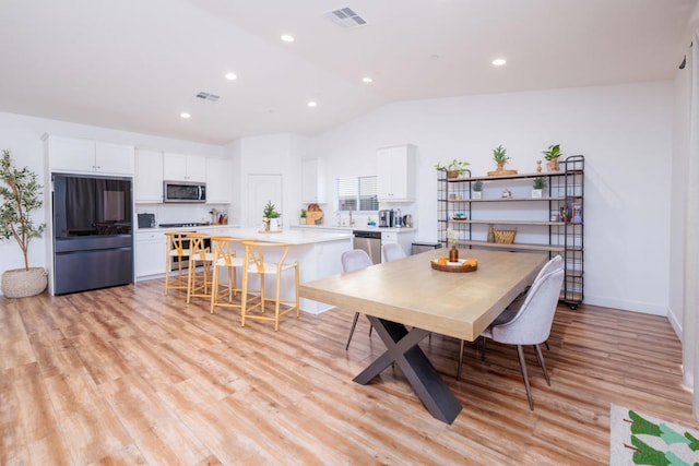 dining space with lofted ceiling and light hardwood / wood-style floors