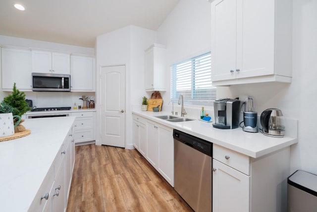 kitchen with sink, white cabinetry, appliances with stainless steel finishes, and light hardwood / wood-style flooring