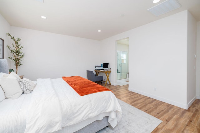 bedroom with connected bathroom and light hardwood / wood-style flooring