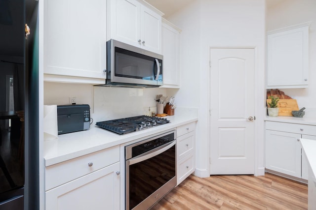 kitchen with white cabinetry, appliances with stainless steel finishes, and light wood-type flooring