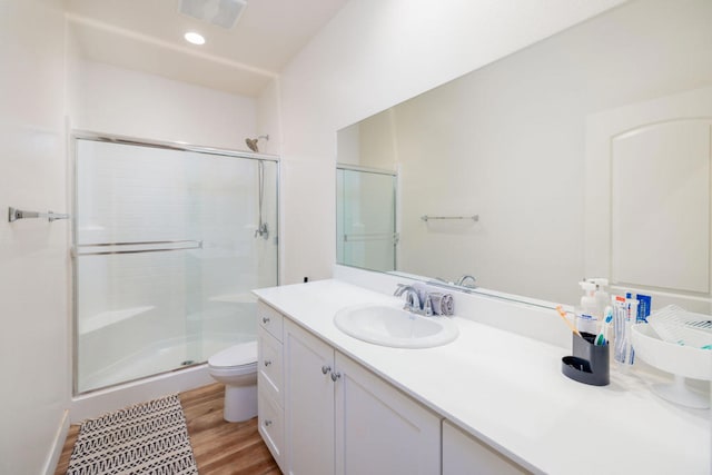 bathroom featuring hardwood / wood-style flooring, toilet, vanity, and an enclosed shower