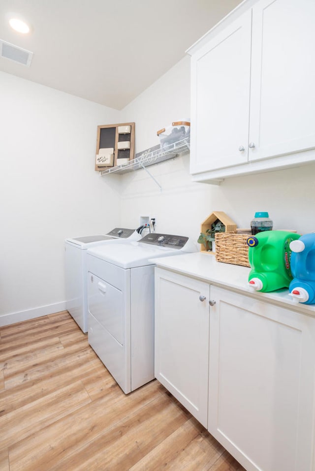 laundry room featuring cabinets, light hardwood / wood-style flooring, and washing machine and clothes dryer