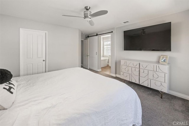 carpeted bedroom featuring ceiling fan, a barn door, a closet, and ensuite bath