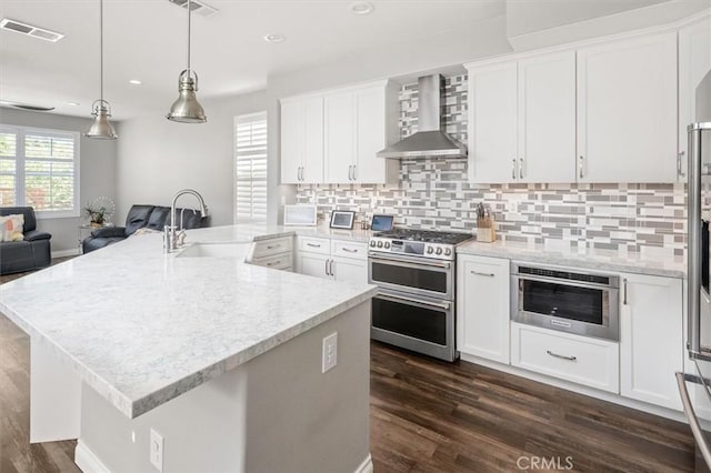 kitchen featuring white cabinets, appliances with stainless steel finishes, and wall chimney exhaust hood