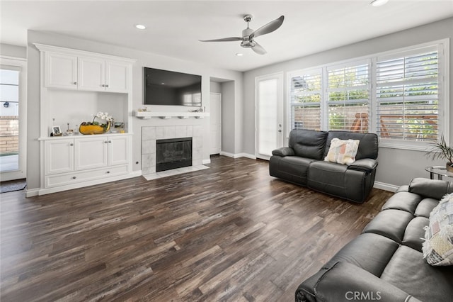 living room with ceiling fan, a tile fireplace, and dark hardwood / wood-style flooring