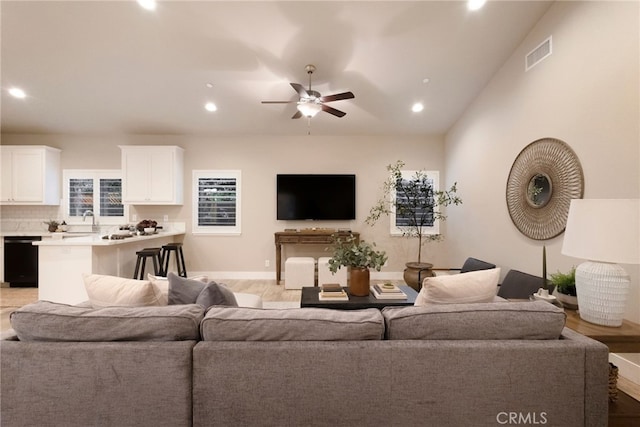 living room with light wood-type flooring, ceiling fan, and sink