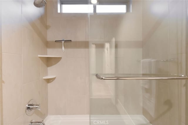 bathroom featuring combined bath / shower with glass door