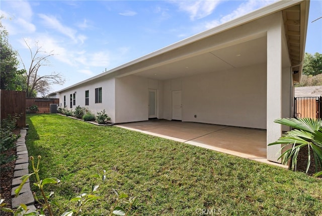 rear view of property with a patio area, central air condition unit, and a lawn