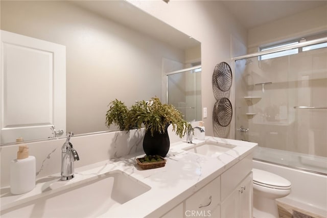 full bathroom with bath / shower combo with glass door, toilet, and vanity