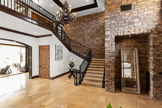 foyer with a high ceiling, crown molding, and a notable chandelier