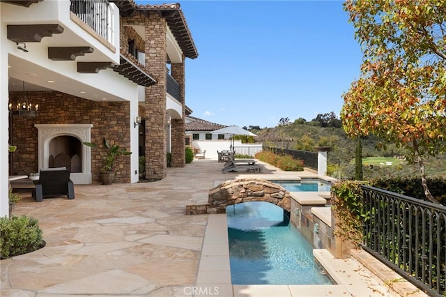 view of patio / terrace with a balcony and a swimming pool with hot tub