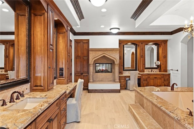 bathroom with hardwood / wood-style flooring, a relaxing tiled tub, vanity, and ornamental molding