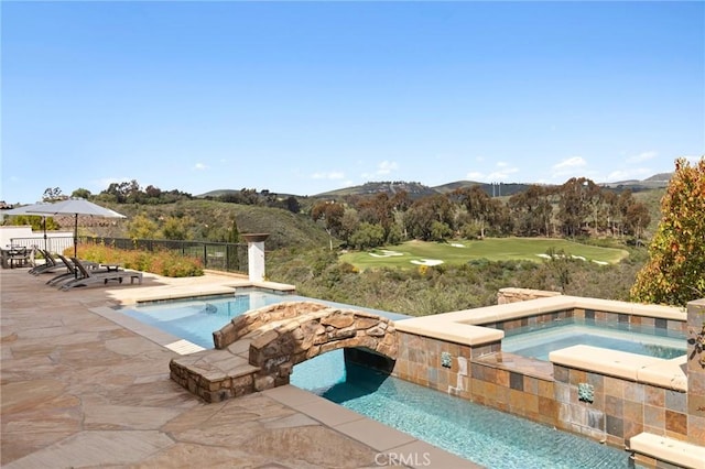 view of pool featuring an in ground hot tub, a mountain view, and a patio