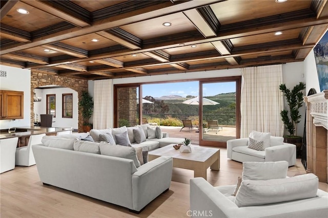 living room featuring light hardwood / wood-style floors, a mountain view, coffered ceiling, and beamed ceiling