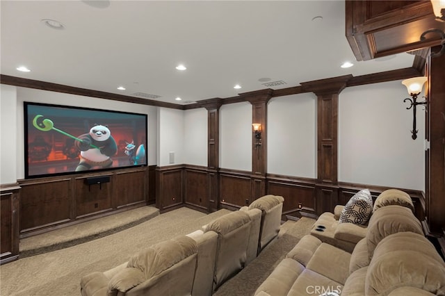 carpeted home theater room featuring ornate columns, crown molding, and wooden walls