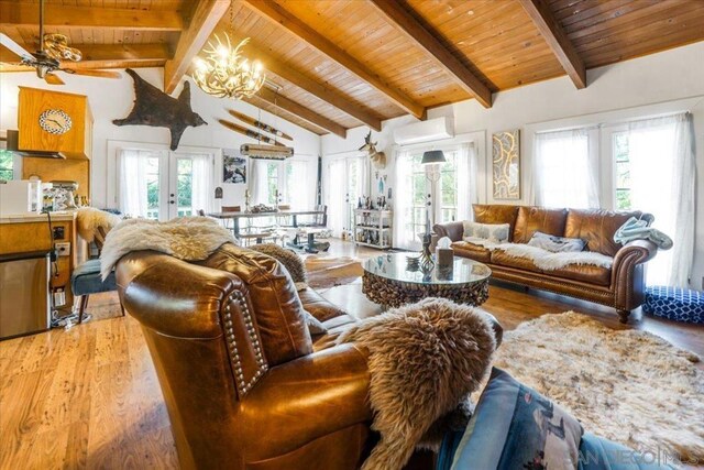 living room with hardwood / wood-style flooring, wooden ceiling, a wall mounted air conditioner, vaulted ceiling with beams, and french doors